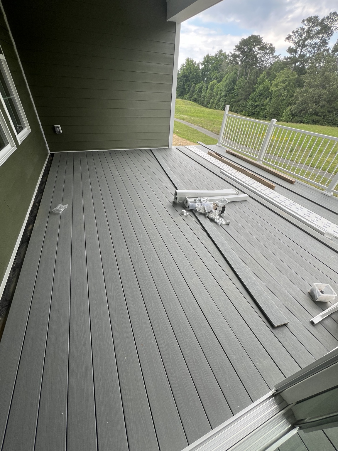 Covered porch work in progress: Deck-board installation and railing materials onsite